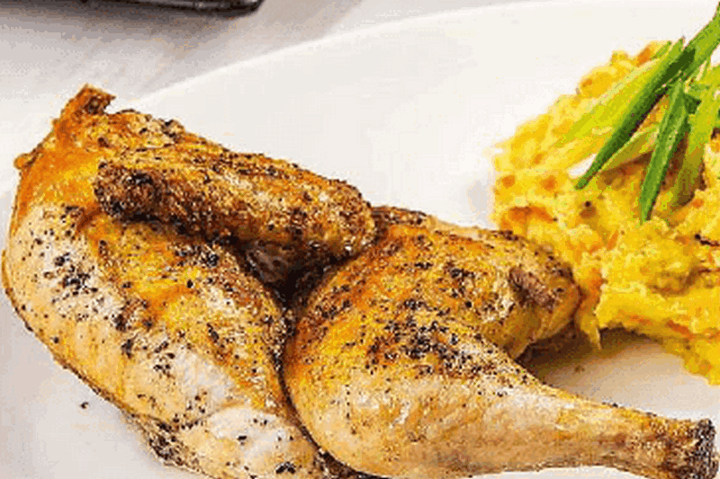 Цыпленок, запеченный с травами, поданный с картофельным пюре, сдобренным луково-чесночным соусом